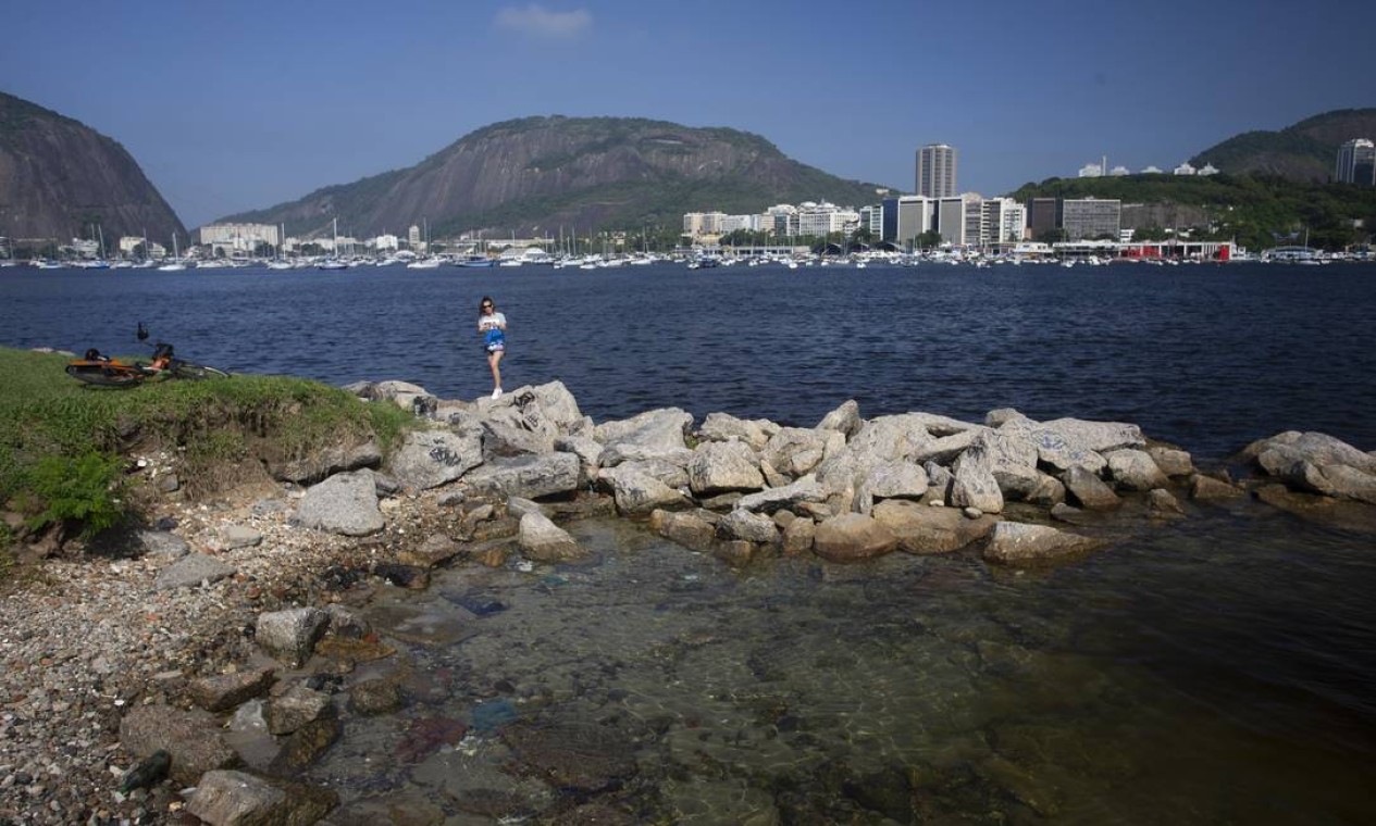 Uma mulher fotografa a Praia de Botafogo em dia de águas claras, o que é raro Foto: Márcia Foletto / Agência O Globo