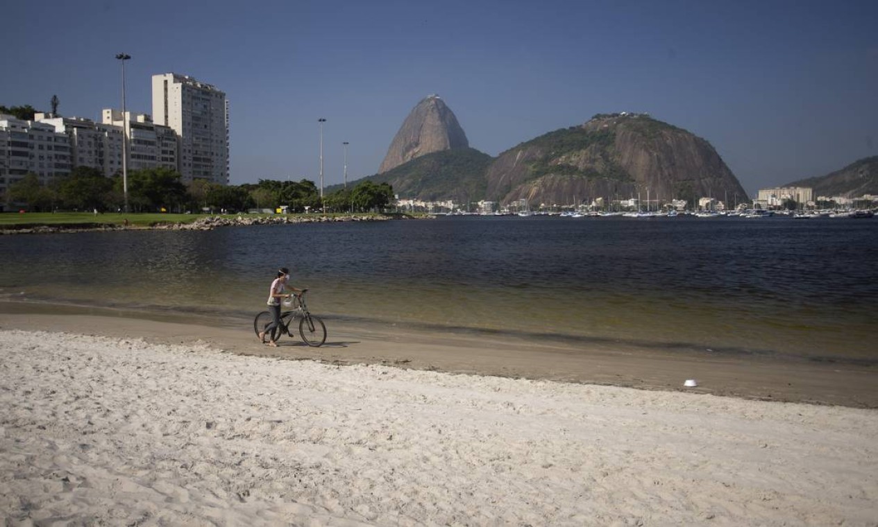 Mulher caminha na Praia de Botafogo, admirando a rara condição das águas Foto: Márcia Foletto / Agência O Globo