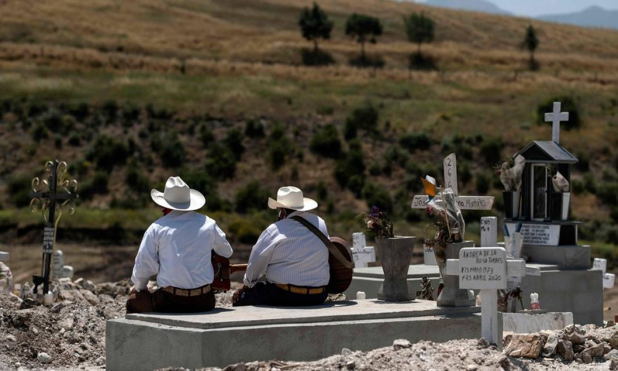 Músicos aguardam por enterro em um cemitério municipal em Tijuana, no estado mexicano de Baixa Califórnia, em meio à nova pandemia de coronavírus. Conhecido mundialmente por sua colorida celebração do Dia dos Mortos, em 2 de novembro, o país das catrinas (caveiras de mulheres) vem sofrendo alterações em seus rituais fúnebres por protocolos rigorosos impostos pela crise da Covid-19 Foto: GUILLERMO ARIAS / AFP