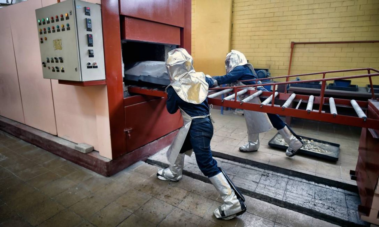 Trabalhadores do panteão municipal de Nezahualcóyotl empurram um corpo para o forno do crematório, em Nezahualcóyotl, subúrbio próximo à Cidade do México Foto: ALFREDO ESTRELLA / AFP