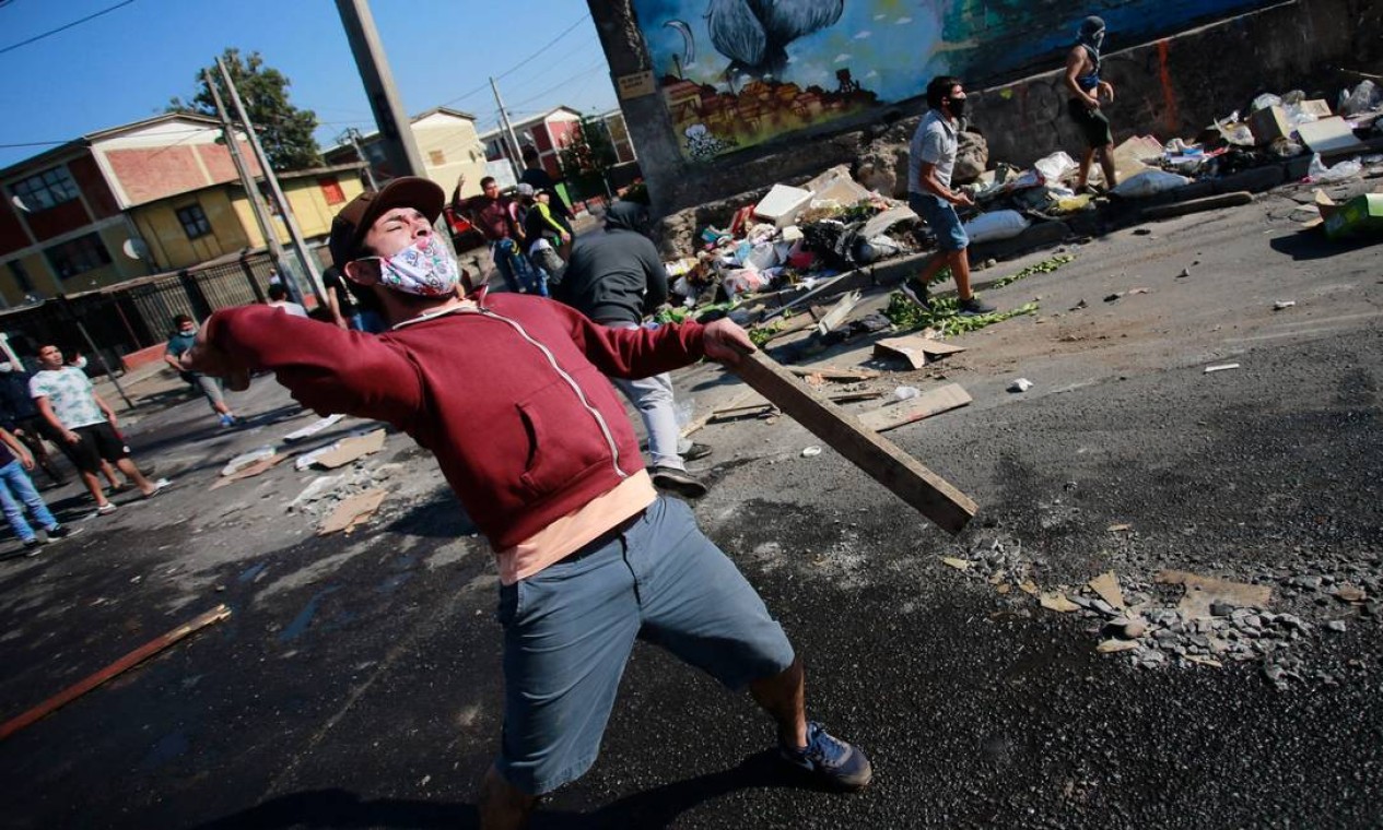 Manifestante atira objetos contra a polícia de choque durante um protesto contra o governo do presidente Sebastián Piñera Foto: PABLO ROJAS / AFP