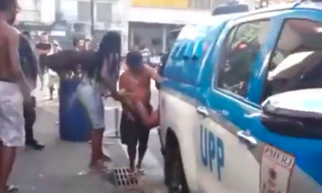 Em vídeo compartilhado por moradores, é possível ver momento em que policiais colocam homem baleado dentro da viatura em meio a protestos Foto: Reprodução