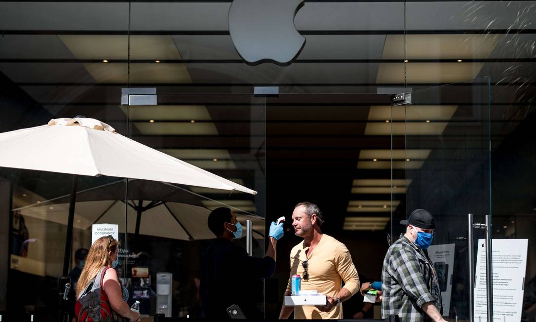 Demanda em alta. Segurança mede temperatura de cliente na porta de uma loja da Apple em Charleston, nos EUA Foto: Sean Rayford / AFP