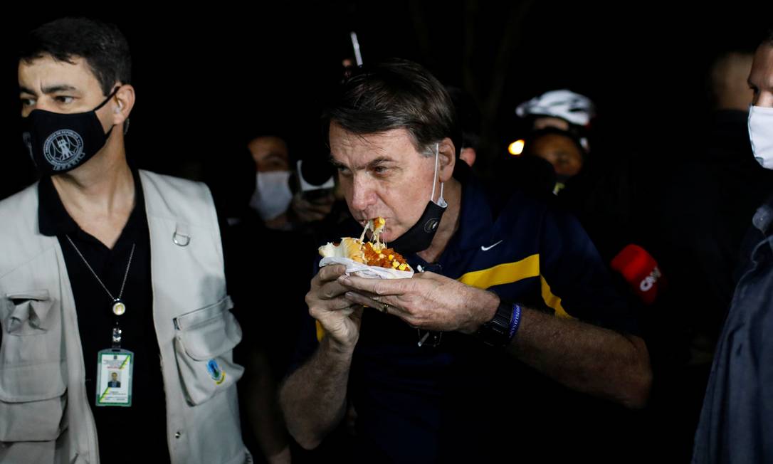 Bolsonaro come cachorro-quente, em um trailer, em Brasília Foto: ADRIANO MACHADO / REUTERS