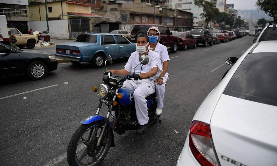 Profissionais da saúde aguardam em fila para abastecer motocicleta em posto de gasolina em Caracas Foto: FEDERICO PARRA / AFP