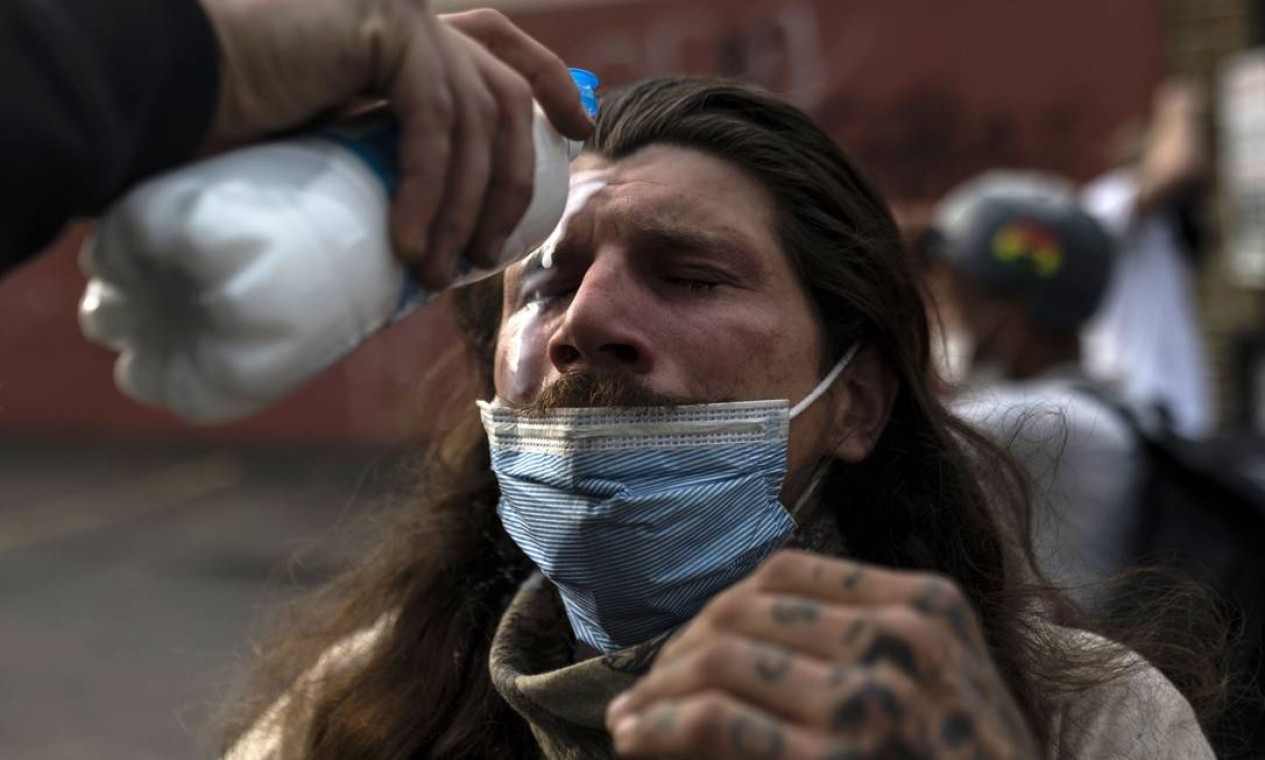 Manifestante lava rosto depois de ser atingido por spray de pimenta da polícia em Mineápolis, Minessota, onde o aconteceu a barbárie Foto: Stephen Maturen / AFP