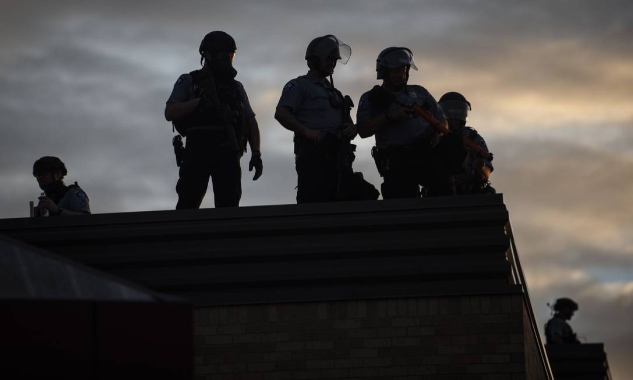 Policiais observam manifestação do alto de um terraço, em Mineápolis Foto: Stephen Maturen / AFP