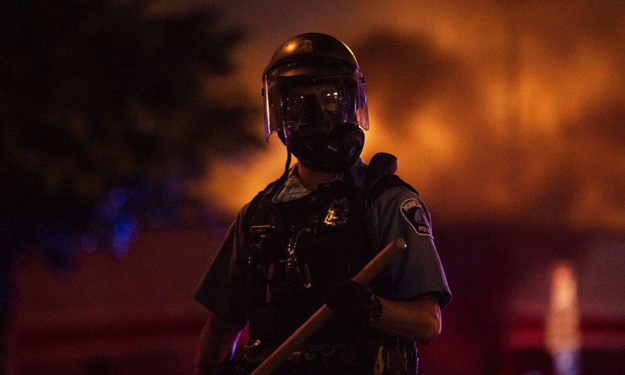 Policial empunha cacetete em meio a protestos na noite de quarta-feira, quando população revoltada com a morte de George Floyd chegou a atear fogo e saquear lojas em Mineápolis Foto: Stephen Maturen / AFP
