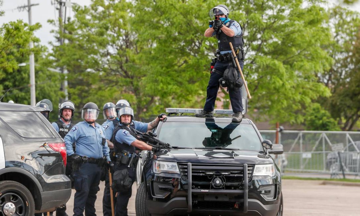 Policial, de cima do teto de carro oficial, mira em manifestantes em Mineápolis Foto: ERIC MILLER / REUTERS