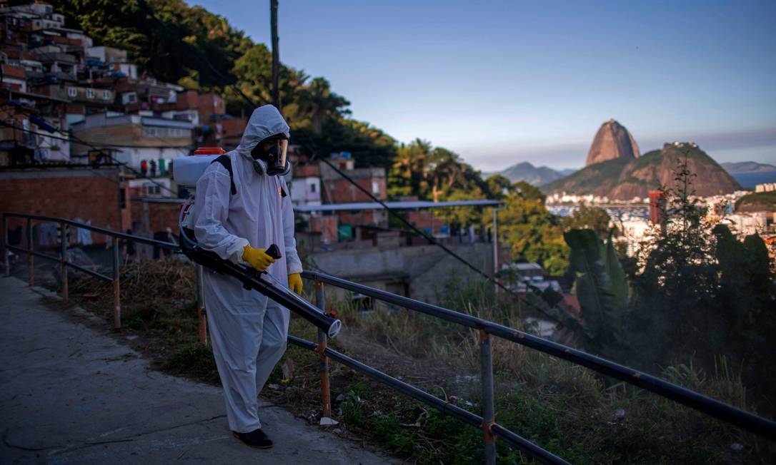 Voluntário desinfeta uma via na favela Santa Marta, no Rio de Janeiro Foto: MAURO PIMENTEL / AFP - 20/04/2020