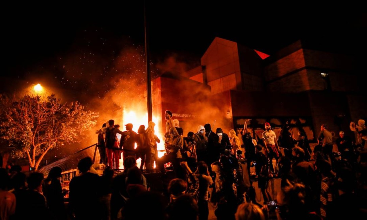 Manifestantes se reúnem depois de atear fogo na entrada de uma delegacia em Minneapolis Foto: CARLOS BARRIA / REUTERS
