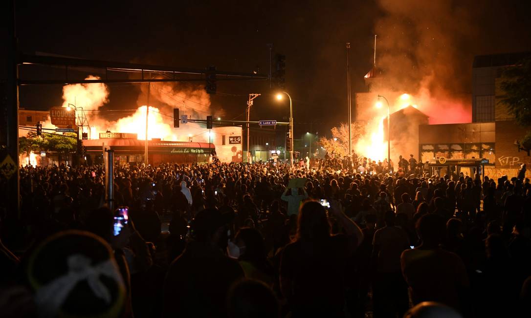 Milhares de pessoas protestam contra o assassinato de George Floyd em Minneapólis; ao fundo, claridade mostra imóveis incendiados Foto: NICHOLAS PFOSI / REUTERS