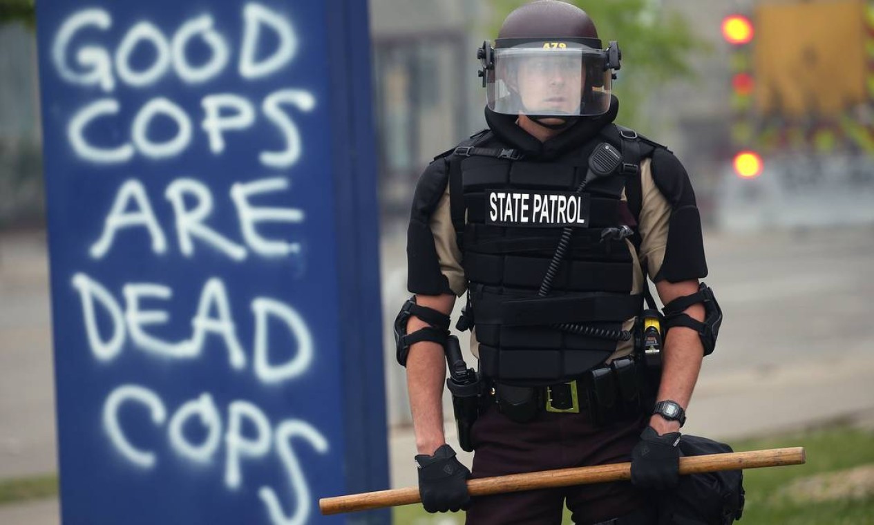 Agente da Guarda Nacional, com cacetete empunhado, aparece ao lado de pichaão que diz: "policial bom é policial morto" Foto: SCOTT OLSON / AFP - 29/05/2021