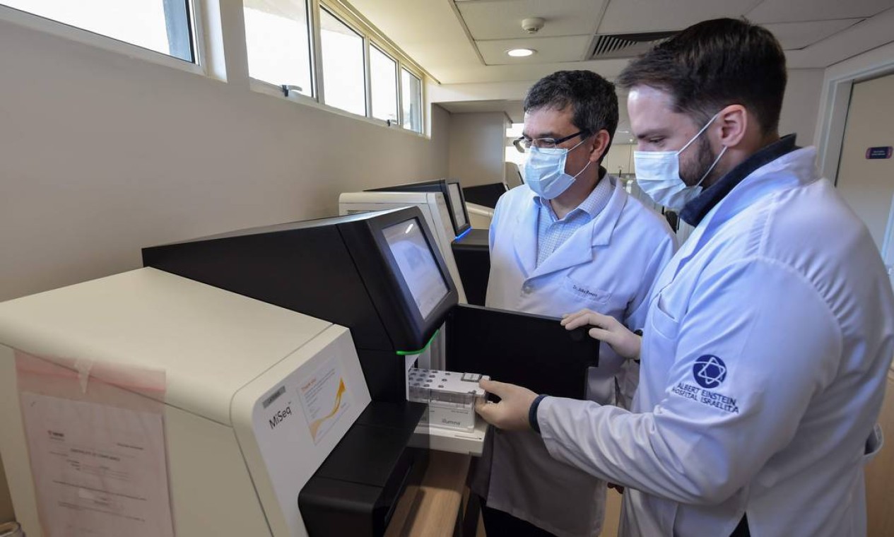 Funcionários introduzem amostras dentro de sequenciador. Resultado em 72 horas Foto: NELSON ALMEIDA / AFP