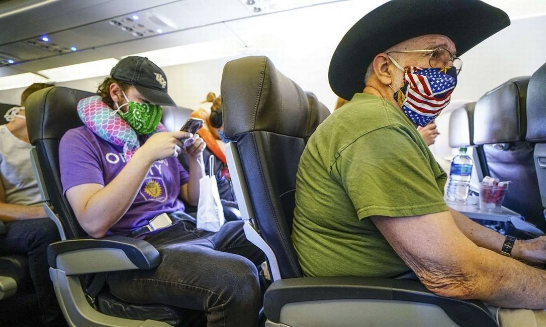 Passageiros usam máscaras a bordo de um voo da American Airlines entre San Diego e Charlotte Foto: Sandy Huffaker / AFP