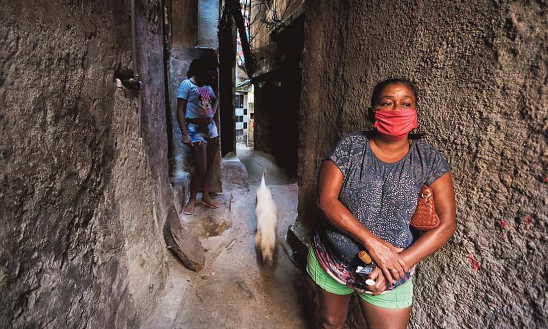 Moradora da Rocinha, onde já houve 55 óbitos, usa máscara em viela: dificuldade para manter distância Foto: Domingos Peixoto / Agência O GLOBO