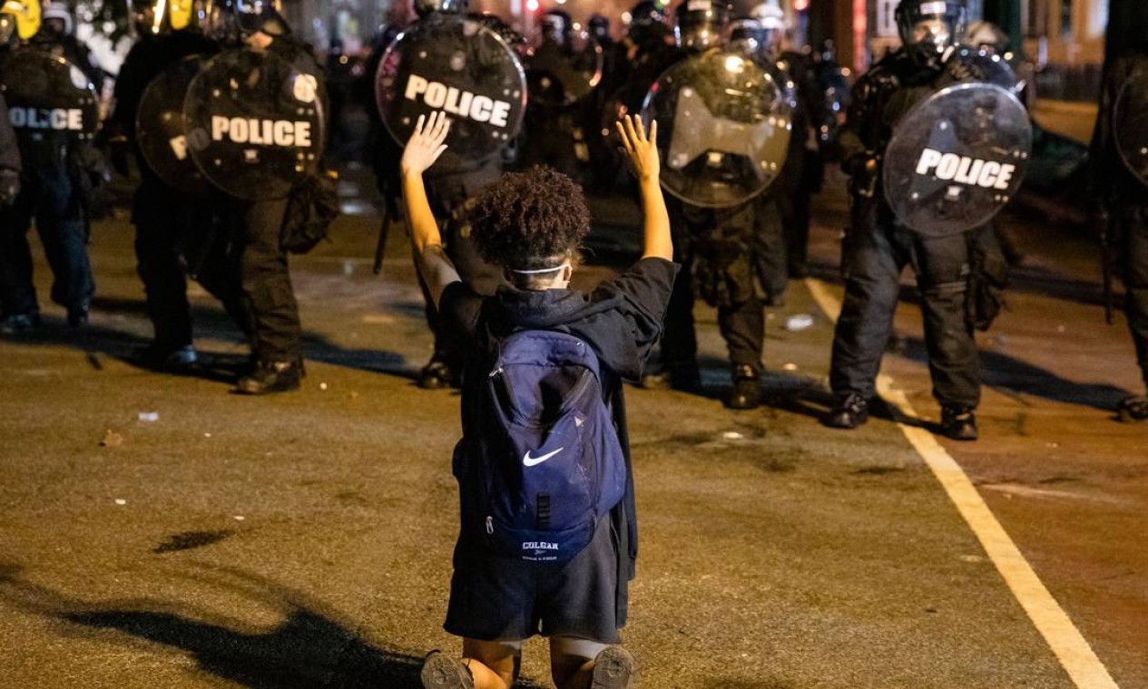 Manifestante ajoelhado mostra as mãos aos policiais da tropa de choque, durante protesto em Washington Foto: SAMUEL CORUM / AFP