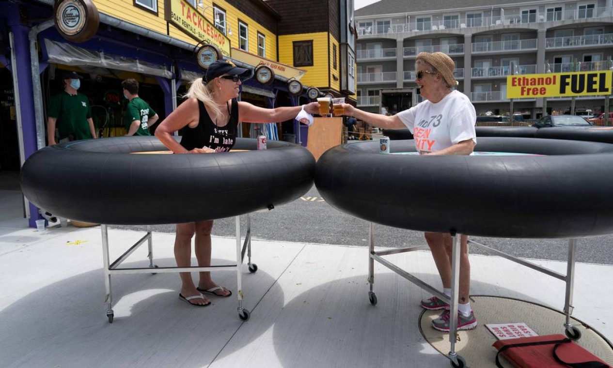 Clientes de um restaurante experimentam dispositivos de distanciamento social feitos de tubos de borracha em meio à pandemia de coronavírus, em Ocean City, Maryland, EUA Foto: ALEX EDELMAN / AFP