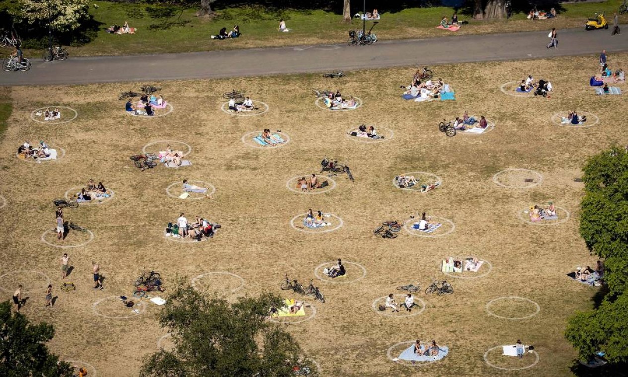 Pessoas aproveitam o sol no parque no Euromast, em Roterdão, na Holanda, enquanto usam círculos marcados para as medidas de distância social Foto: SEM VAN DER WAL / AFP