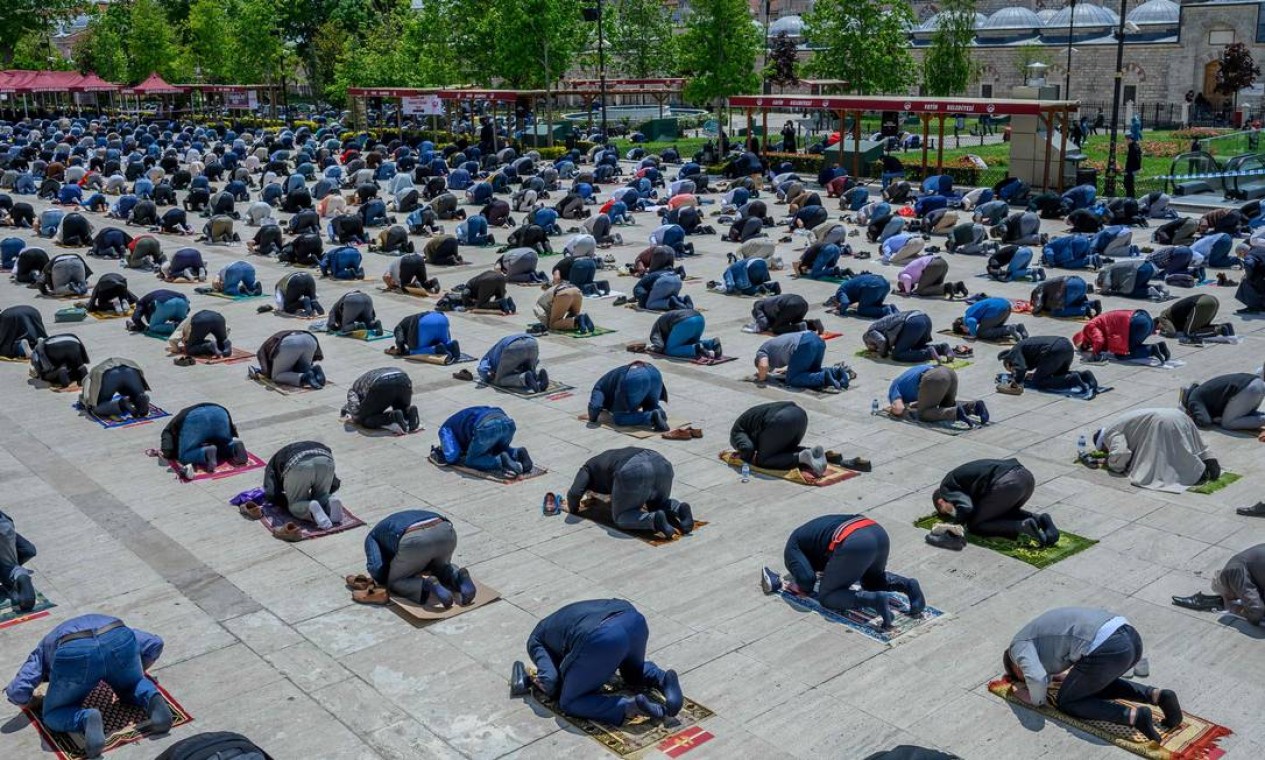 Muçulmanos usam máscaras protetoras enquanto mantêm a distância social necessária durante a oração em frente à Mesquita Fatih, em Istambul Foto: BULENT KILIC / AFP