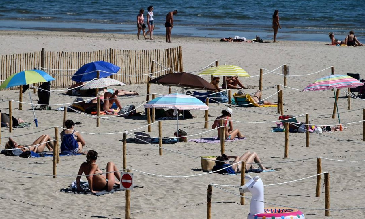 Pessoas tomam banho de sol em Sunset Beach, com áreas separadas para respeitar a distância social em La Grande-Motte, no sul da França Foto: PASCAL GUYOT / AFP