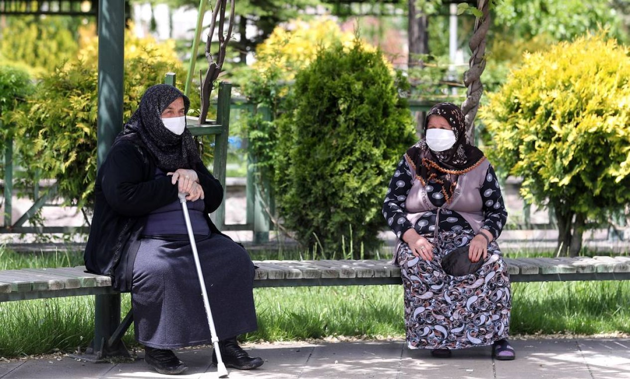 Idosos, usando máscaras protetoras, sentam-se em um banco de um parque do distrito de Akyurt, na Turquia Foto: ADEM ALTAN / AFP