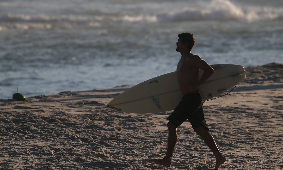 Surfista caminha na Praia de Ipanema: atividade é uma das que voltam a ser autorizadas a partir desta terça-feira Foto: Luiza Moraes / Agência O Globo