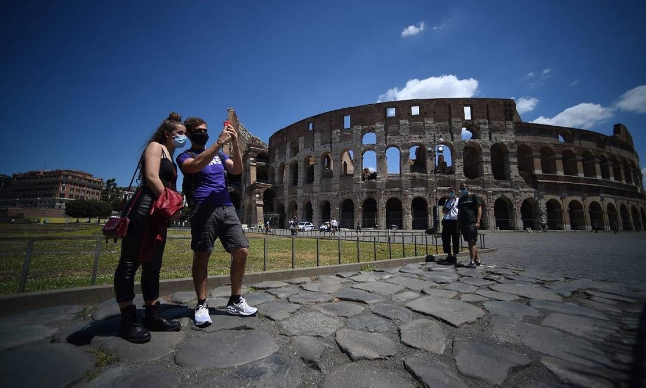Pessoas posam em frente ao Coliseu, em Roma, a atração turística mais visitada da Itália Foto: FILIPPO MONTEFORTE / AFP