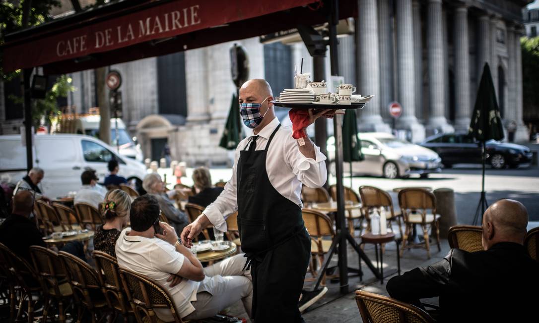 Garçom trabalhando em café de Paris no primeiro dia em que os estabelecimentos foram autorizados a reabrir no país Foto: Martin Bureau / AFP