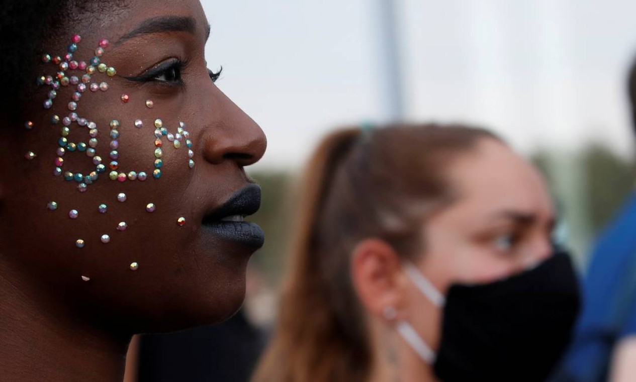 Em Paris, mulher negra carrega no rosto a mensagem #BLM, sigla para "black lives matter" ("vidas negras importam", em inglês), ao lado de uma branca que usa máscara de proteção, durante manifestação proibida em memória de Adama Traore, negro francês de 24 anos morto pela polícia em 2016 Foto: GONZALO FUENTES / REUTERS