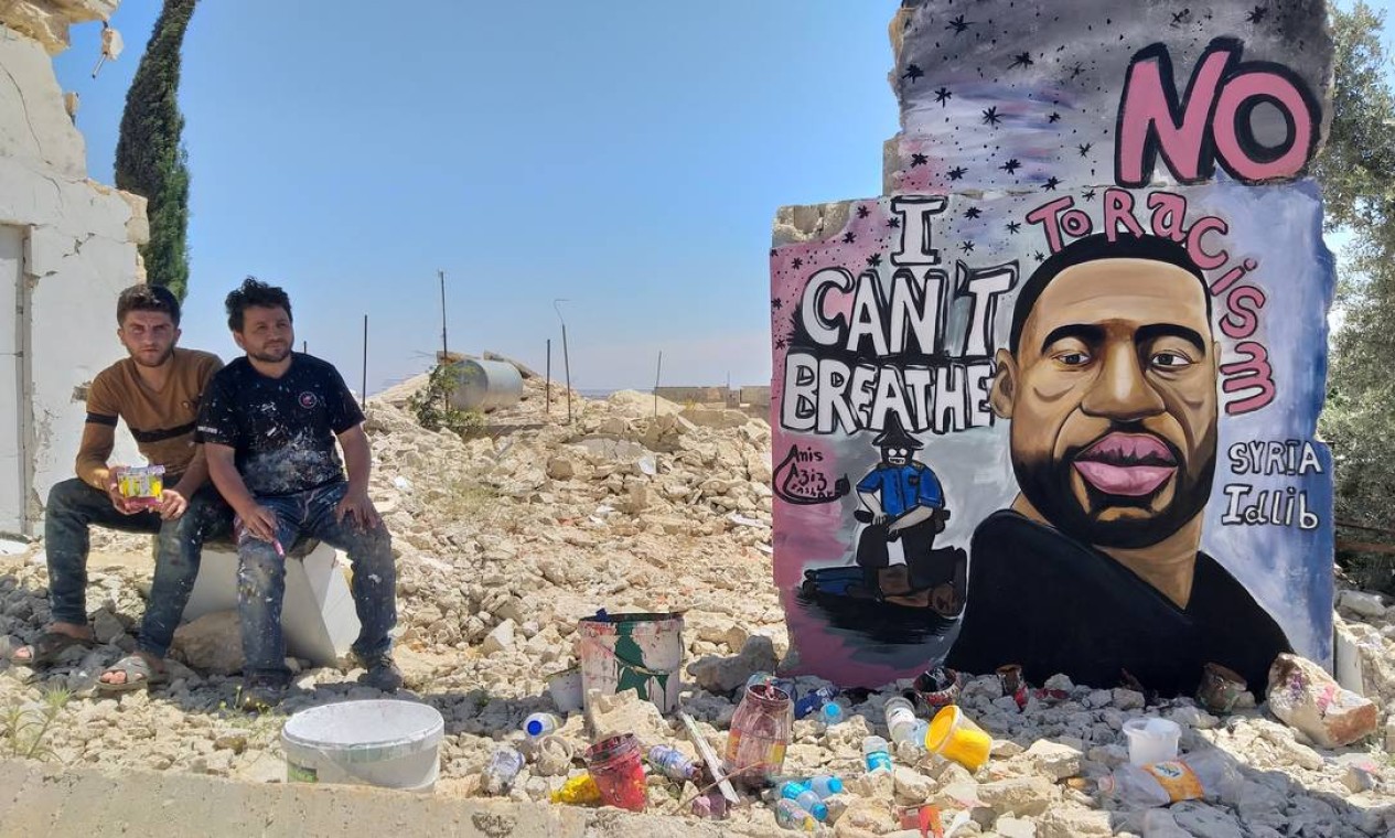 Artistas Aziz Asmr e Anis Hamdoun posam próximo a grafite com a imagem de George Floyd, em Idlib, na Síria, na segunda-feira, quando o assassinato completou uma semana Foto: MOHAMAD JAMALO / REUTERS - 01/07/2020