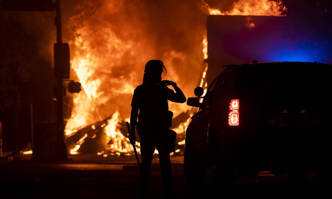 Policial em frente a uma loja que foi queimada por manifestantes em Minneapolis Foto: Stephen Maturen / AFP