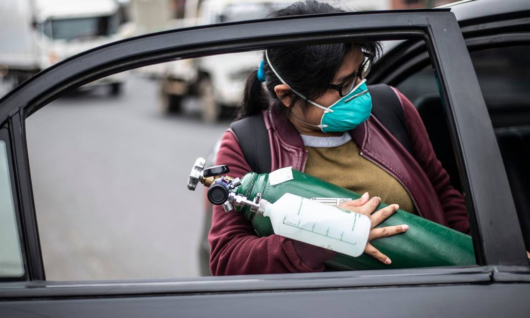 Mulher carrega cilindro de oxigênio vazio para recarregá-lo no Hospital 2 de Mayo, em Lima Foto: ERNESTO BENAVIDES / AFP/03-06-2020