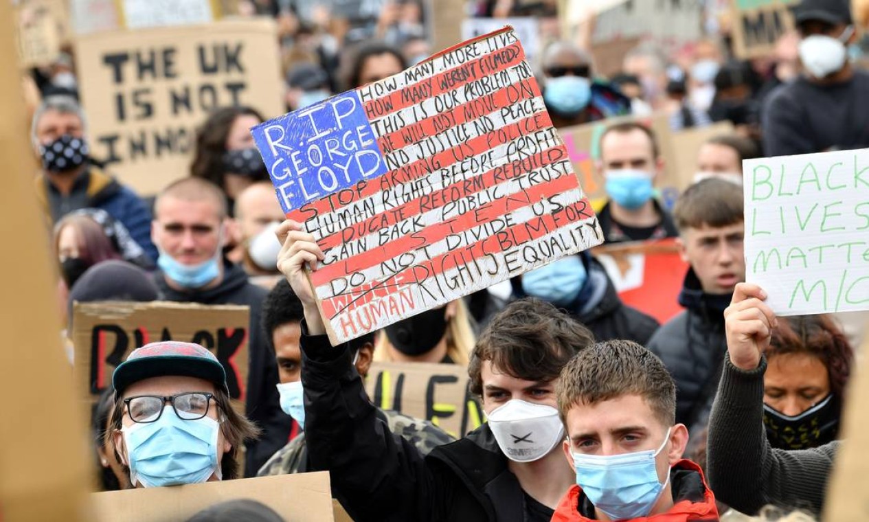 Manifestantes, alguns usando EPI (equipamento de proteção individual) de máscara facial como medida de precaução contra o COVID-19, seguram cartazes enquanto participam de uma manifestação em Manchester, norte da Inglaterra, neste sábado Foto: PAUL ELLIS / AFP