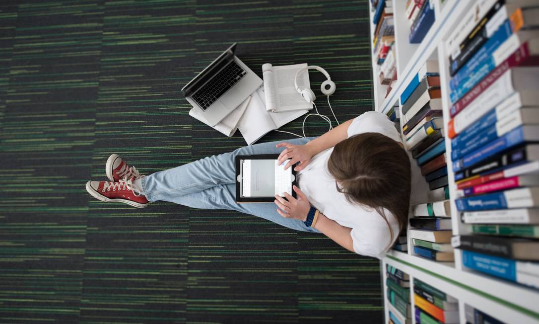 Estudante sentado no chão de biblioteca Foto: Arquivo
