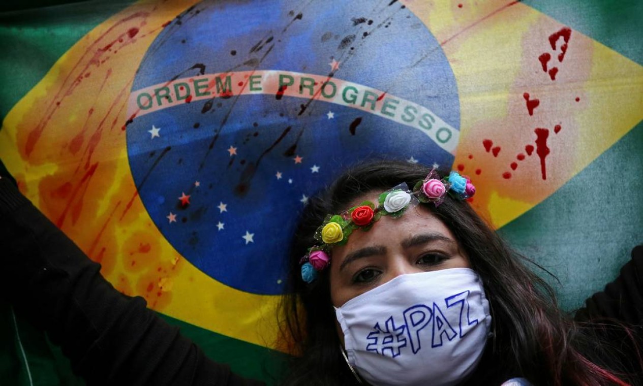 Manifestante segura bandeira do Brasil manchada em protesto contra Bolsonaro, em Porto Alegre Foto: DIEGO VARA / REUTERS