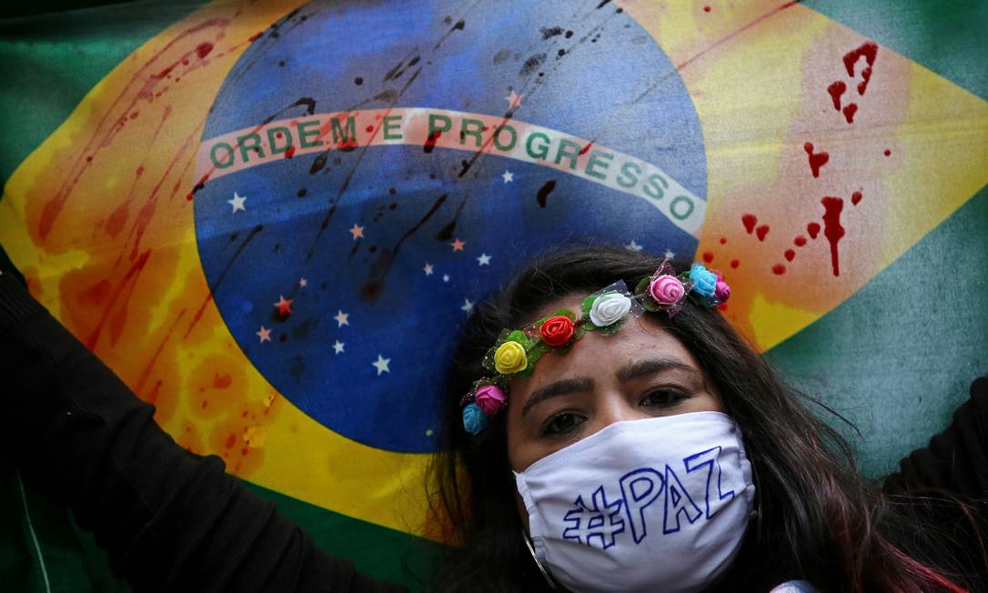 Manifestante segura bandeira do Brasil manchada em protesto contra Bolsonaro, em Porto Alegre Foto: DIEGO VARA/REUTERS / DIEGO VARA/REUTERS