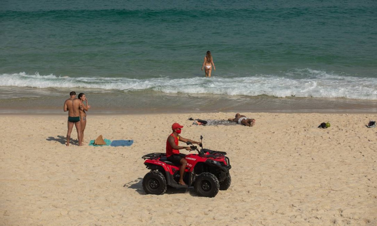 Salva-vida patrulha a Praia da Barra enquanto pessoas tomam banho de mar, o que está proibido pelos decretos do estado e do município Foto: BRENNO CARVALHO / Agência O Globo