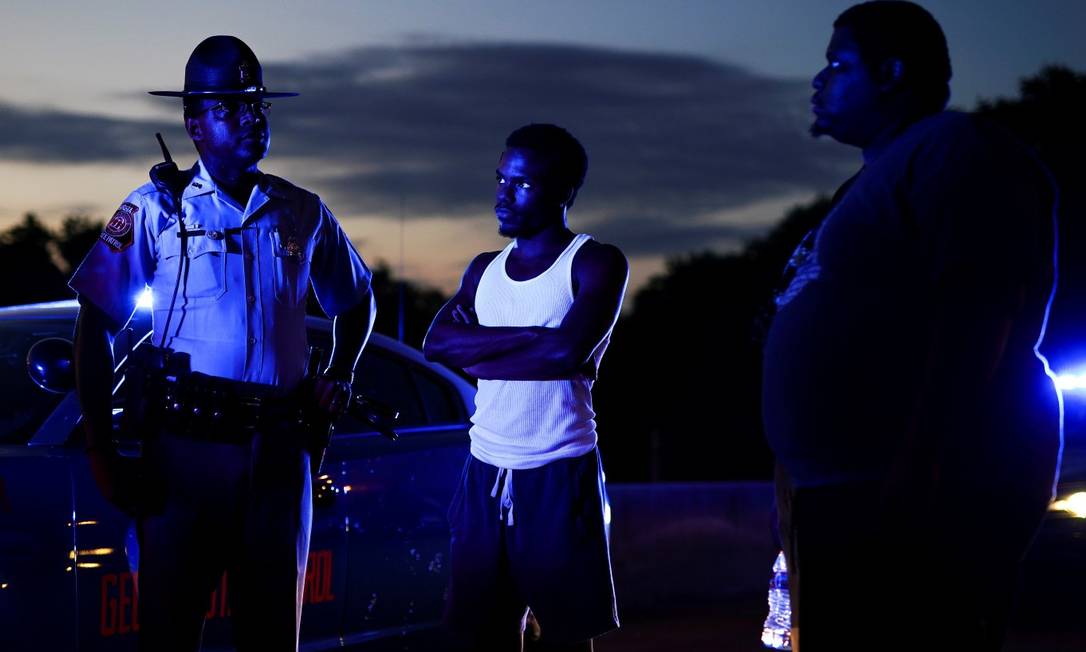 Dois manifestantes conversam com um policial após bloquearem uma rodovia durante uma manifestação contra a desigualdade racial e a morte de Rayshard Brooks, em Atlanta, na Geórgia Foto: ELIJAH NOUVELAGE / REUTERS