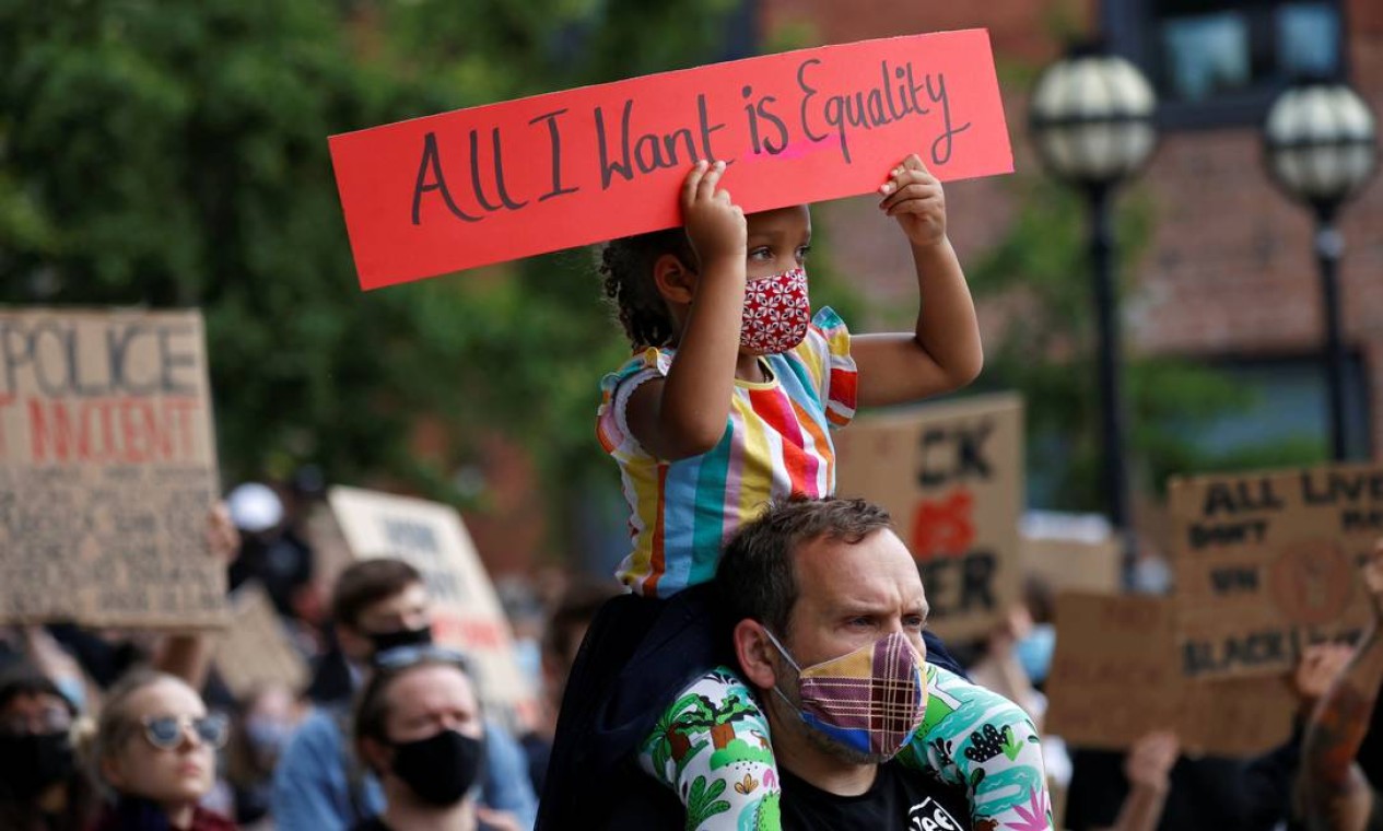 Uma pequena manifestante sentada nos ombros de um homem segura uma placa em que se lê "tudo que eu quero é igualdade", em Leeds, Inglaterra Foto: PHIL NOBLE / REUTERS