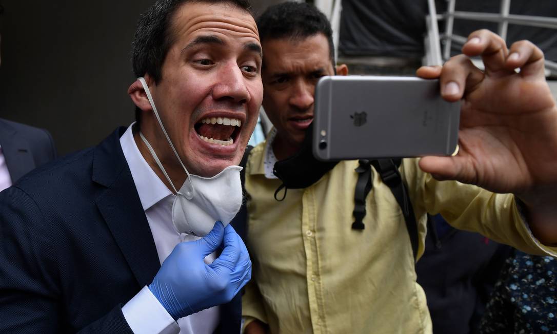 Juan Guaidó, reconhecido como presidente interino da Venezuela por mais de 50 países, posa sem máscara para foto com apoiador em Caracas: oposição enfraquecida Foto: FEDERICO PARRA / AFP
