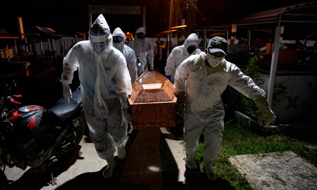 Coveiros em trajes de proteção carregam o caixão de uma vítima do novo coronavírus no cemitério Recanto da Paz, no Pará Foto: TARSO SARRAF / AFP