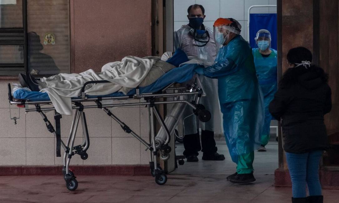 No Hospital San Jose, em Santiago, profissionais da Saúde transferem um paciente com Covid-19 Foto: MARTIN BERNETTI / AFP