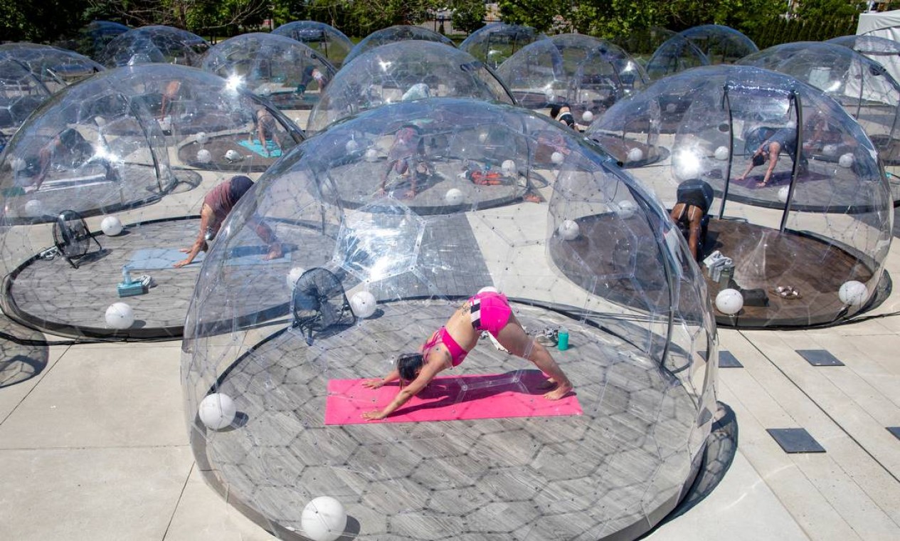 Praticantes de ioga participam de uma aula ao ar livre dentro de estruturas que mantêm o distanciamento social, em Toronto, Canadá Foto: CARLOS OSORIO / REUTERS