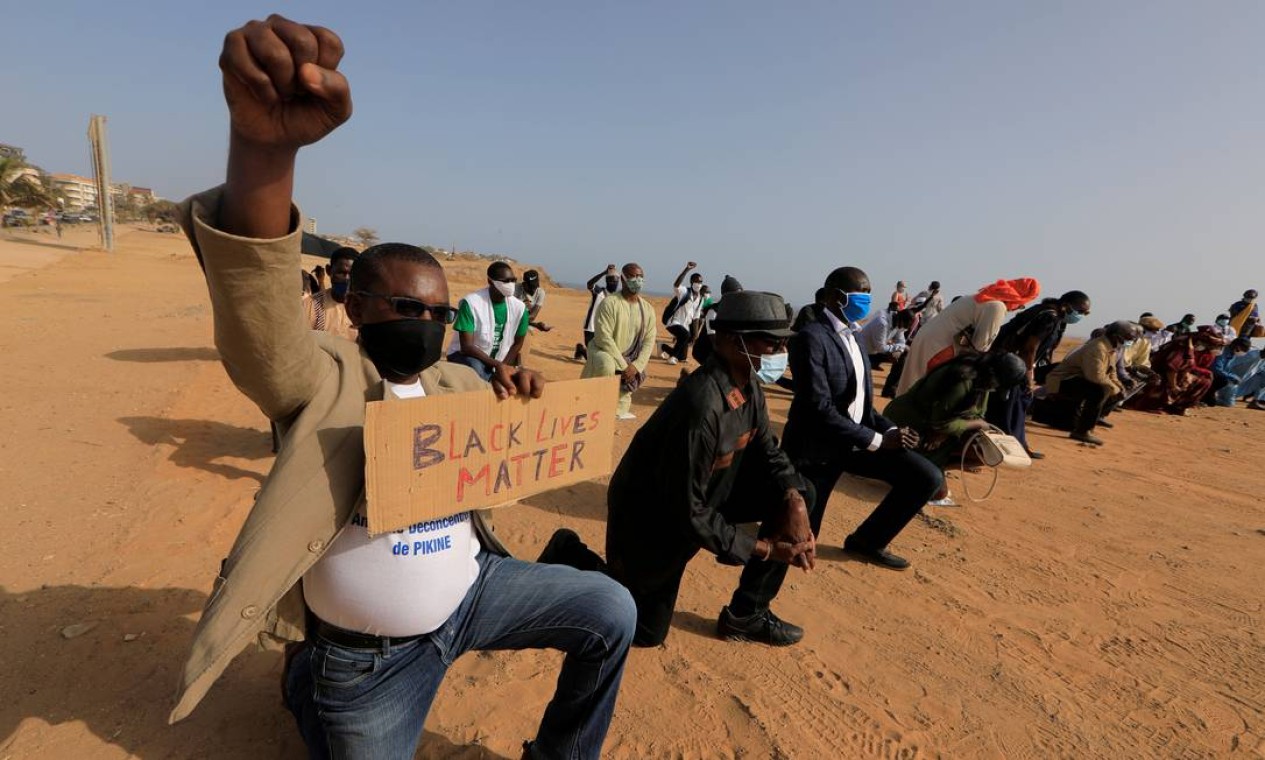 Senegaleses se ajoelham e erguem o punho cerrado, gesto eternizado pelo movimento Panteras Negras, durante a luta por direitos civis nos EUA, em protesto em Dakar Foto: ZOHRA BENSEMRA / REUTERS - 09/06/2020