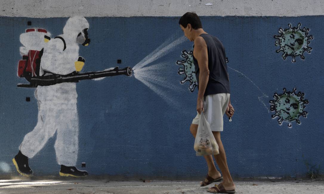 Homem caminha sem máscara em frente a grafite no Bairro do Estácio, Zona Norte do Rio de Janeiro Foto: Luiza Moraes / Agência O Globo