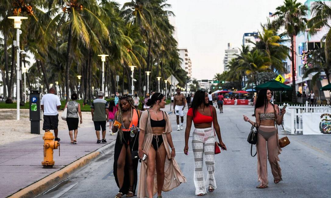 Sem máscaras, mulheres caminham na Ocean Drive, em Miami Foto: CHANDAN KHANNA / AFP / 24-6-2020