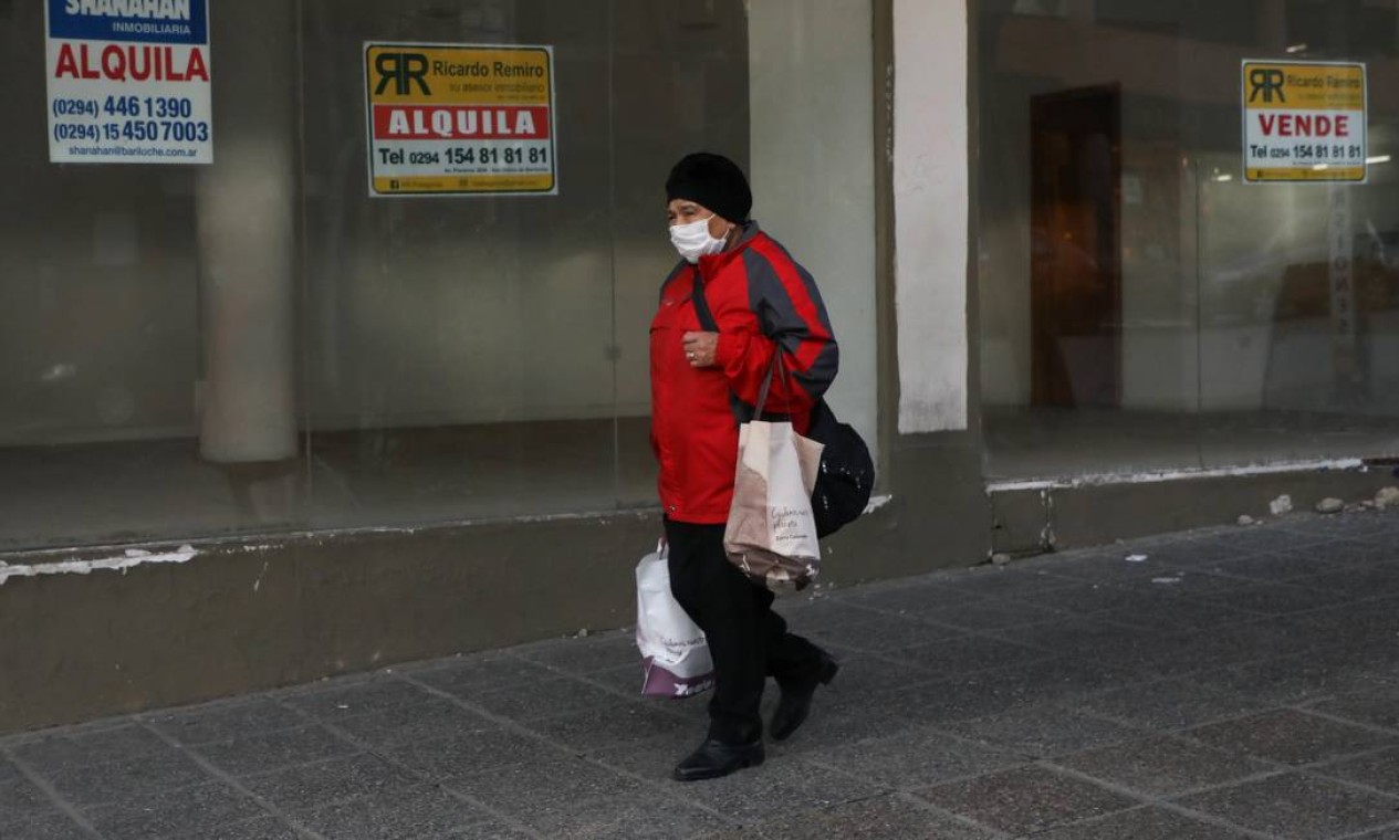 Mulher caminha em frente a lojas com placas de venda e aluguel em Bariloche. Um dos destinos turísticos mais procurados da Argentina sofre as consequências da pandemia Foto: FRANCISCO RAMOS MEJIA / AFP