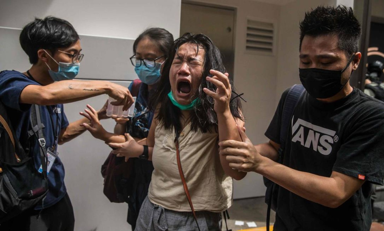 Mulher reage após ser atingida por spray de pimenta pela polícia, que dissipava manifestantes protestando contra a lei de segurança nacional em Hong Kong Foto: DALE DE LA REY / AFP