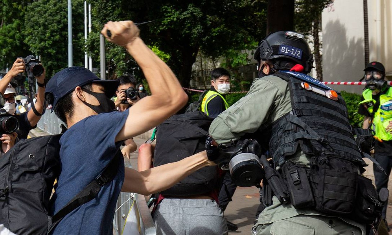 Manifestante usa um objeto afiado contra um policial que está tentando deter um homem durante protesto Foto: ALASTAIR PIKE / AFP